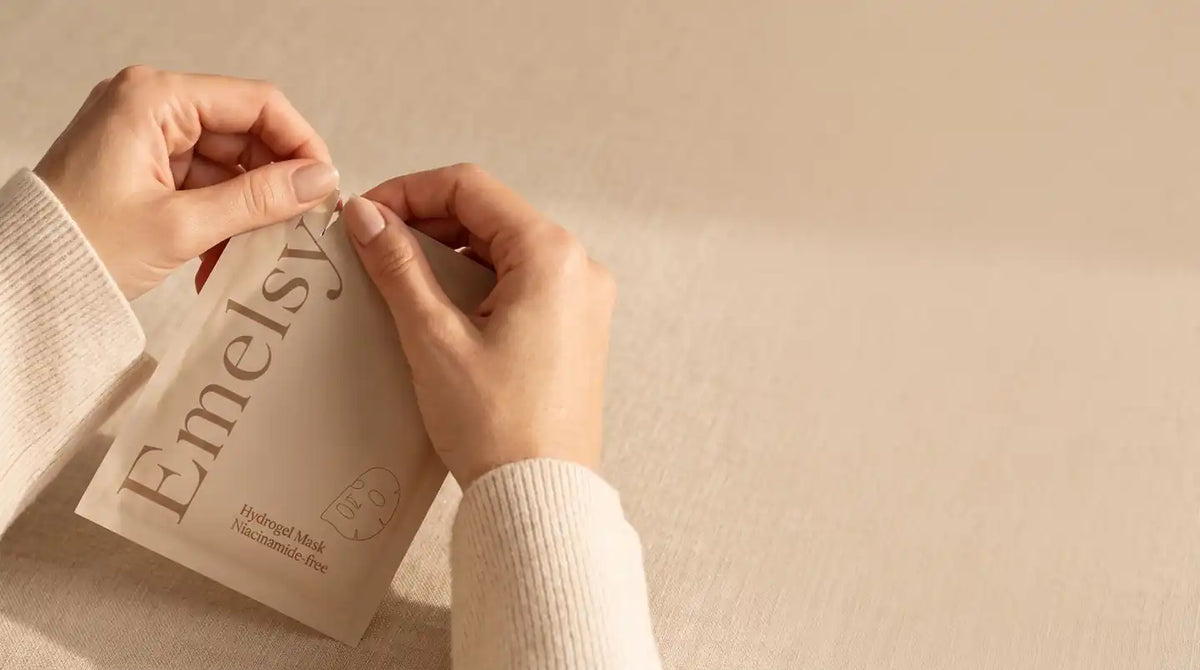Hands opening an Emelsy sachet on soft beige linen